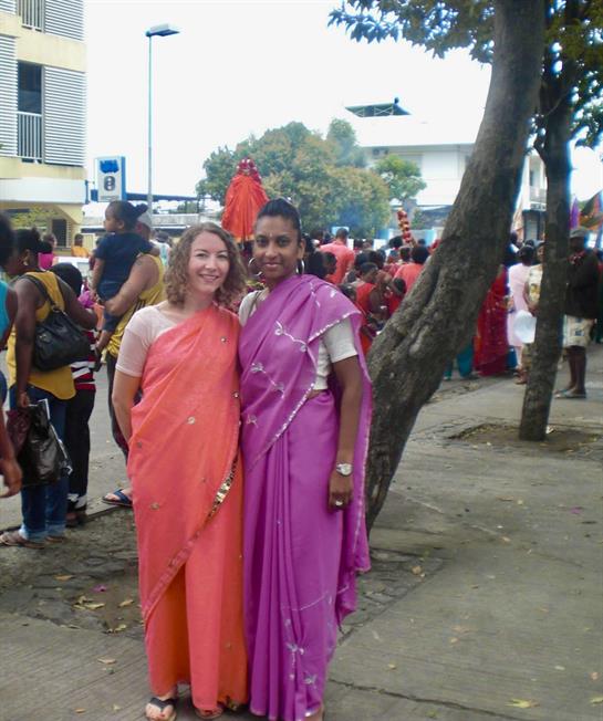 Two women in saris standing on a sidewalk