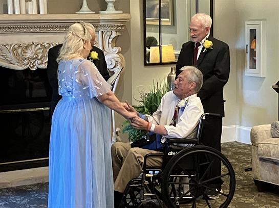 A couple stands before an officiant, exchanging vows while seated and standing guests observe.