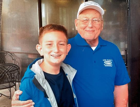 A young boy poses happily with an elderly man at a gathering, showcasing their friendship.