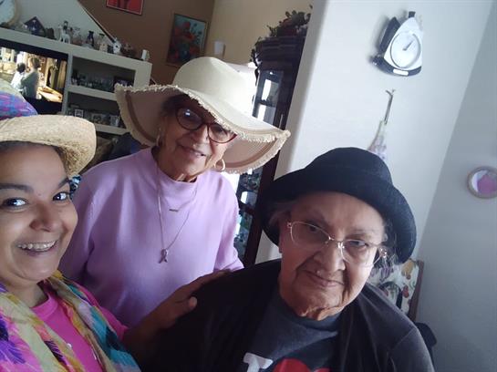 Three friends smile and pose together, wearing stylish hats in a warm, inviting atmosphere.
