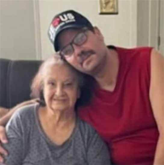 A son embraces his mother on a couch, showcasing warmth and affection in a familiar space.