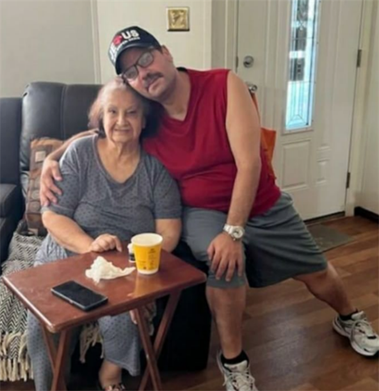 A man embraces his grandmother while sitting together in their comfortable living space.