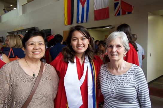 A joyful gathering of three women, celebrating a graduation with smiles and proud expressions.