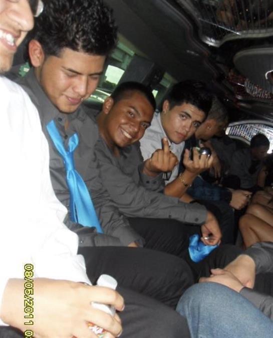 Young men wear elegant attire while celebrating joyfully in a limousine.
