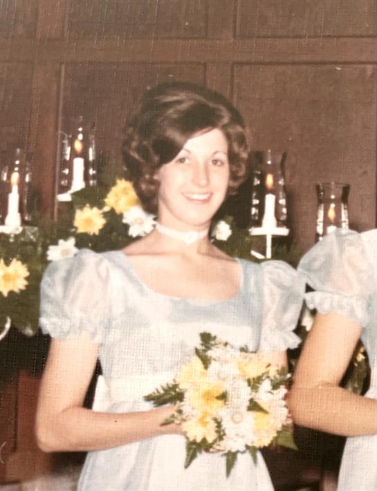 A young woman smiles while holding a bouquet during a joyful celebration in a church.