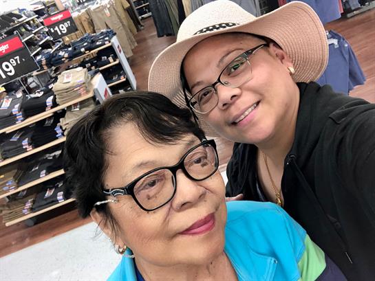 Two family members smile for a selfie while shopping for clothes in a retail store.