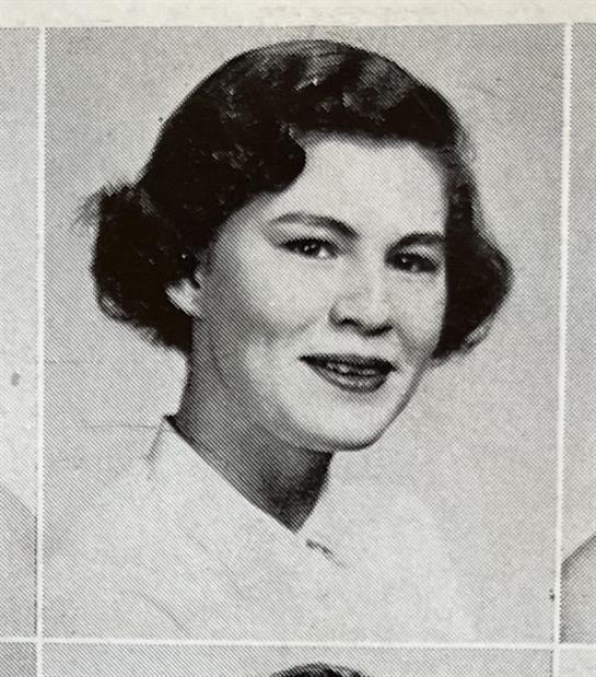 Portrait of a young woman with a charming smile and elegant mid-century hairstyle.