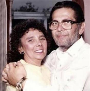 A couple stands closely, sharing a joyful embrace in an inviting indoor atmosphere.