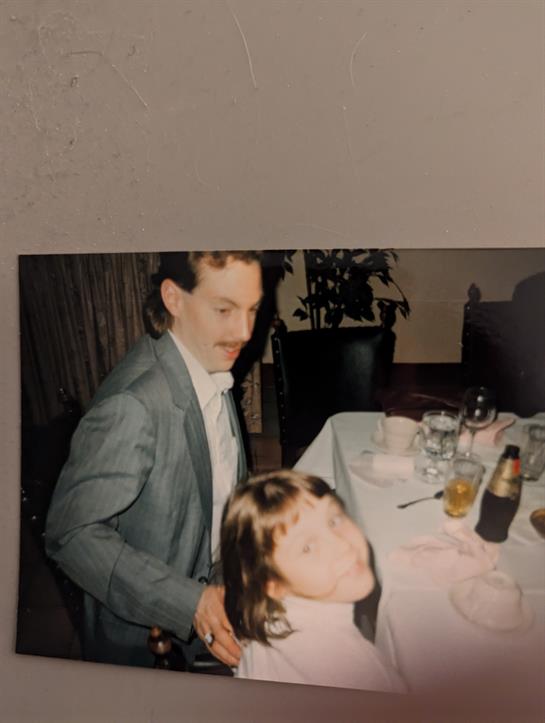A man gently plays with a girl's hair while sitting at a dining table during a celebration.