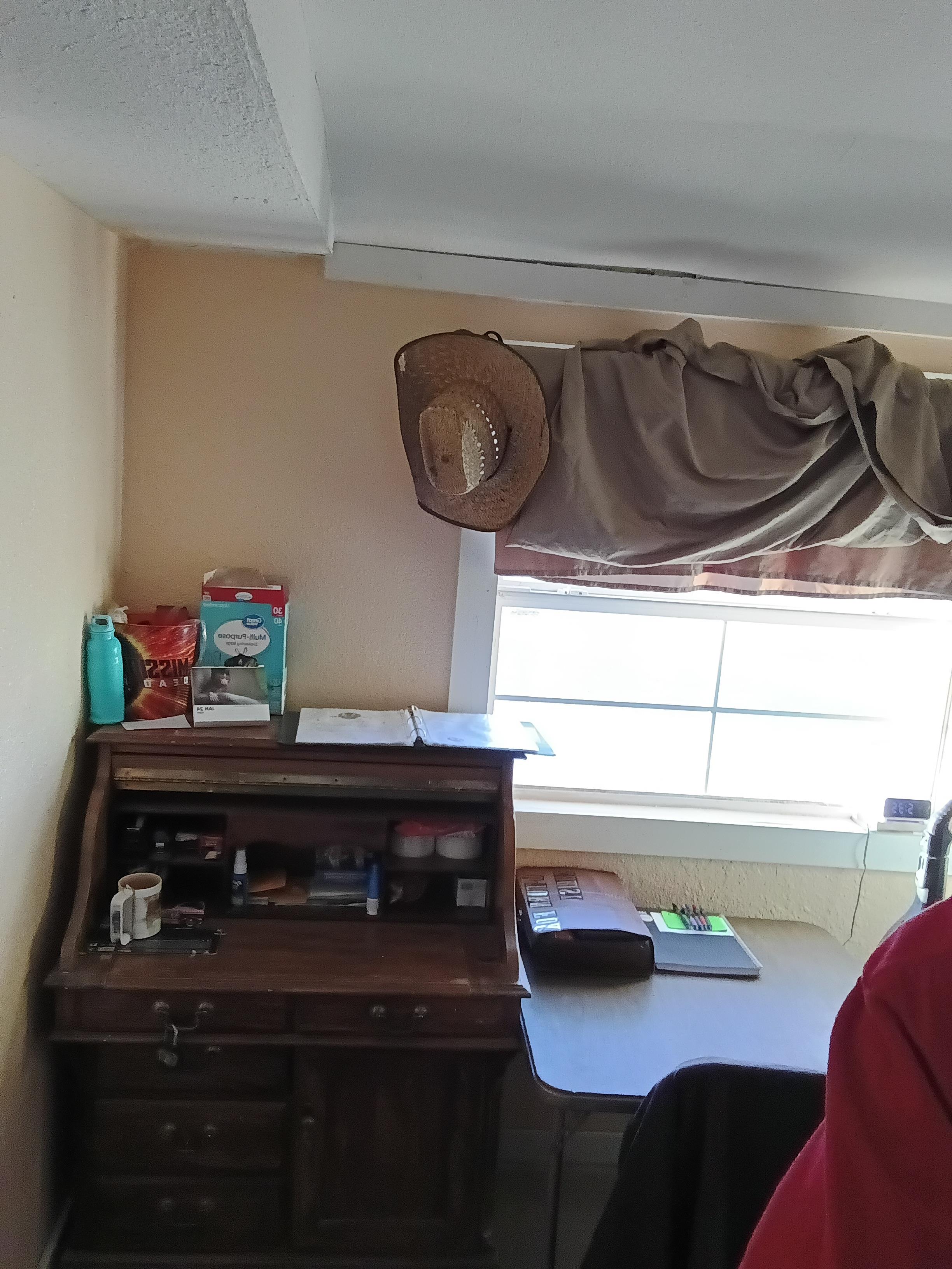 A rustic wooden desk is set against a bright window, creating a warm, inviting atmosphere.