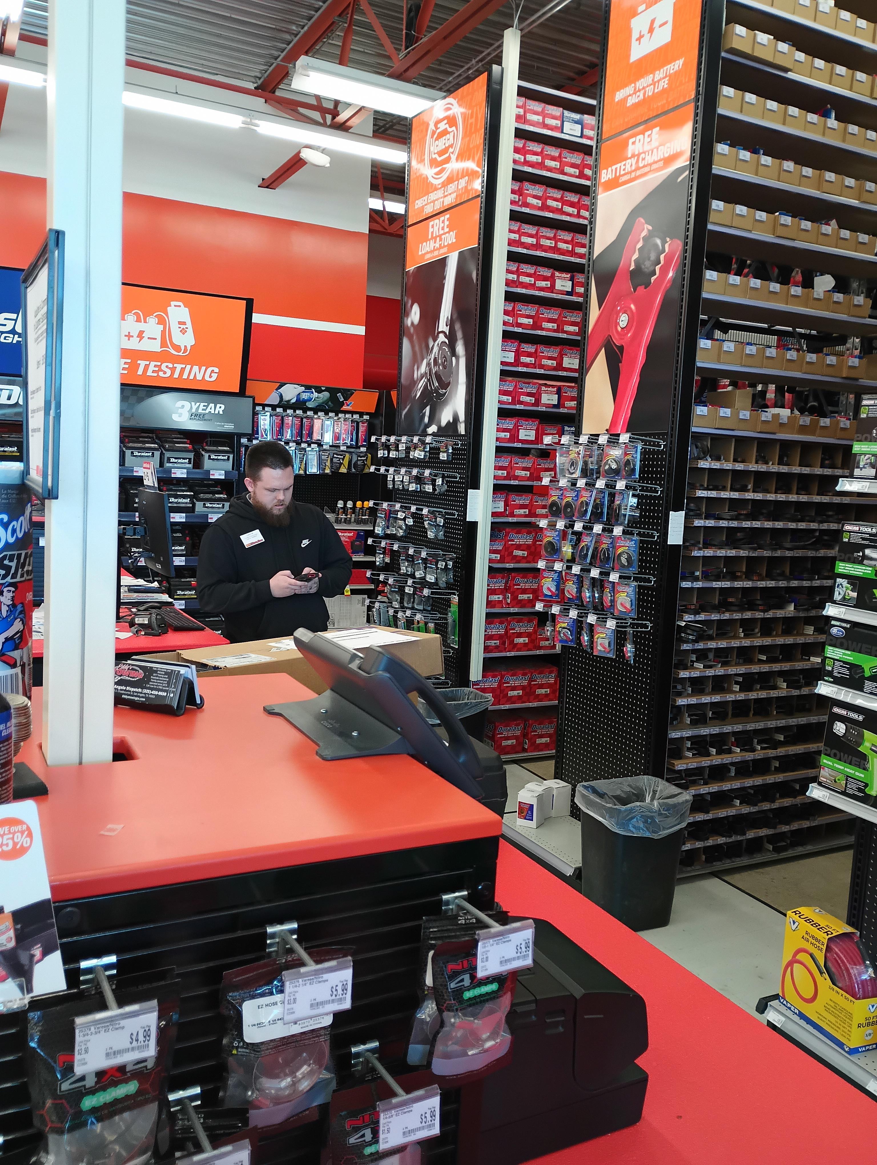 Store interior features various tools displayed on shelves while a staff member assists customers.