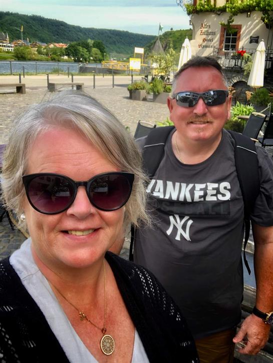 Visitors pose for a cheerful selfie while exploring a vibrant riverside area.