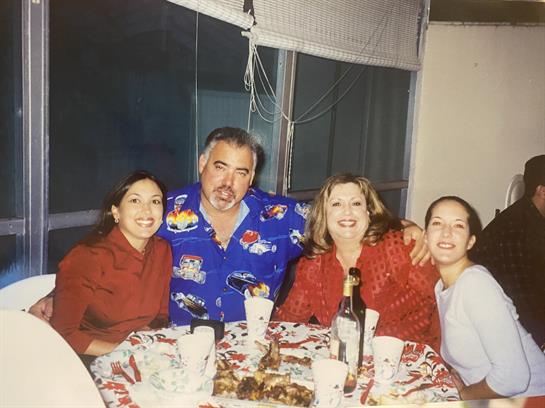 Four friends are smiling and celebrating around a dining table filled with food and drinks.