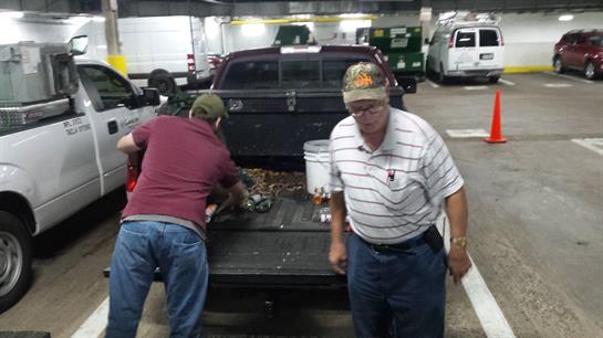Two individuals sort through seafood on the truck bed in a parking garage during the evening.