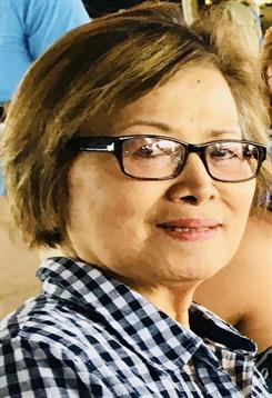 An elderly woman smiles at a relaxed gathering with friends.