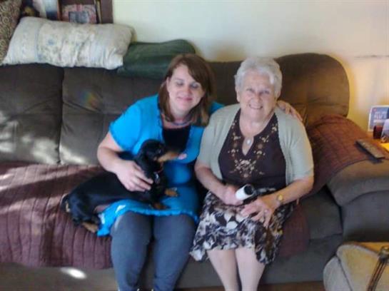 Two women sitting on a couch with a dog