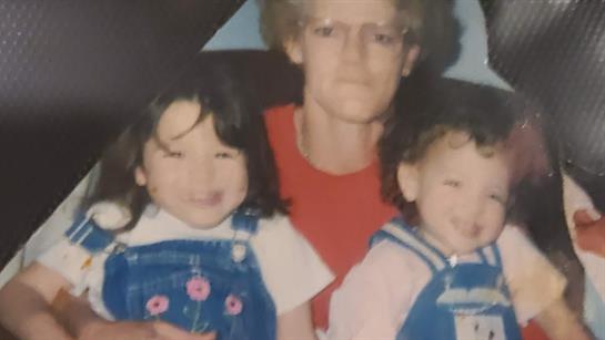 Two smiling children pose with an adult in a relaxed setting, capturing a moment of happiness.