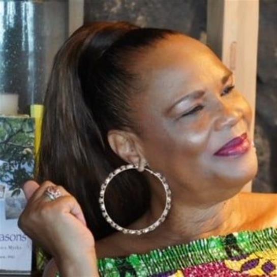 A woman with a stylish ponytail smiles warmly while celebrating at a colorful cultural event.