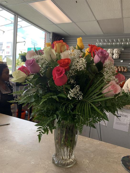 A vibrant arrangement of roses in various colors displayed at a flower shop's counter.