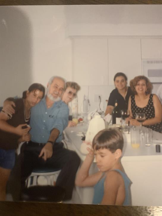 Friends and family gathered around a kitchen table, sharing laughs and drinks.
