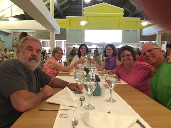 A group of friends gathers around a table, sharing laughter and good food in a lively restaurant.