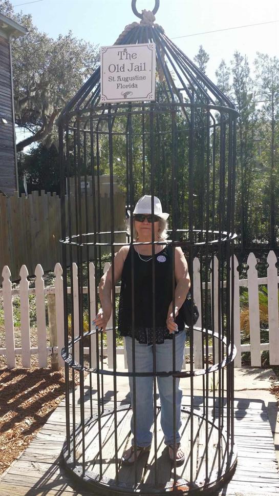 A woman stands playfully inside a vintage jail cell at the Old Jail in St. Augustine, Florida.