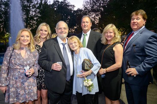 A vibrant gathering of friends enjoying an evening event outdoors near a fountain.