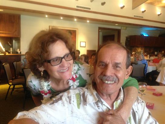 A couple shares a joyful moment at a festive gathering with friends around them.