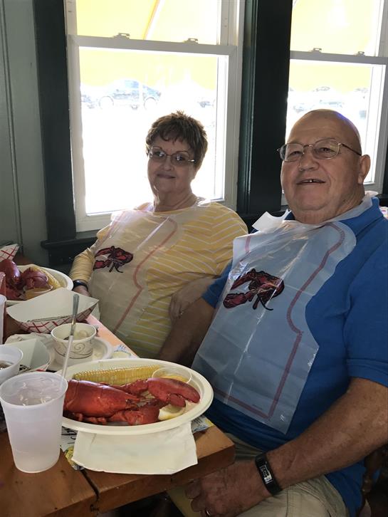 A couple smiles as they enjoy a seafood feast at a charming restaurant by the sea.