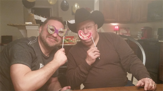 Two friends hold playful props while enjoying a lively gathering in a cozy home setting.