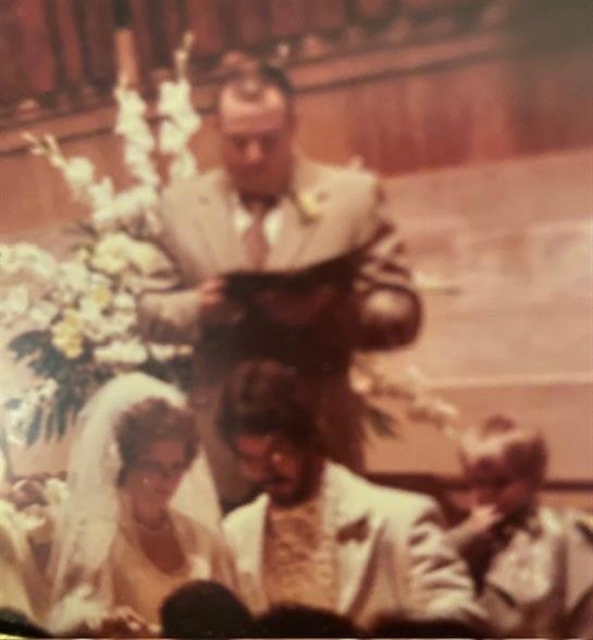 A couple stands together in front of an officiant during a joyful wedding ceremony.
