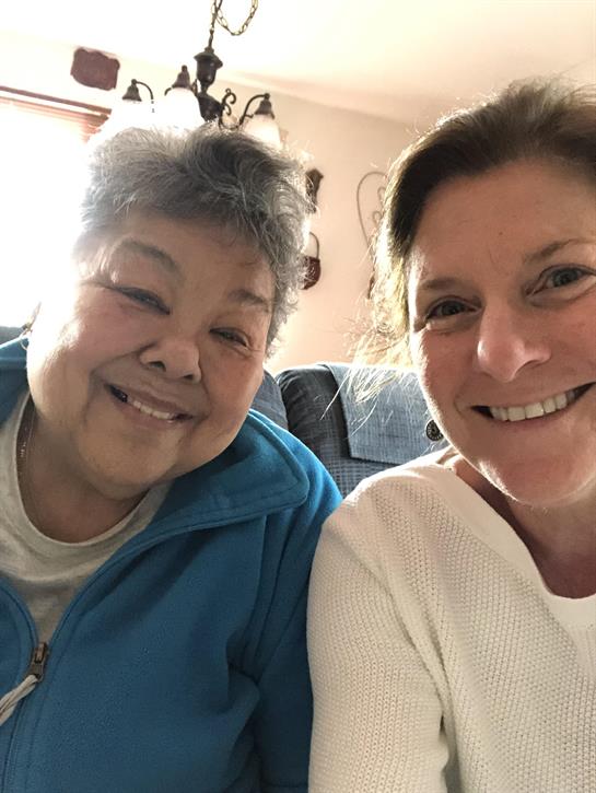 Two smiling women share a joyful moment together in a cozy living room setting.