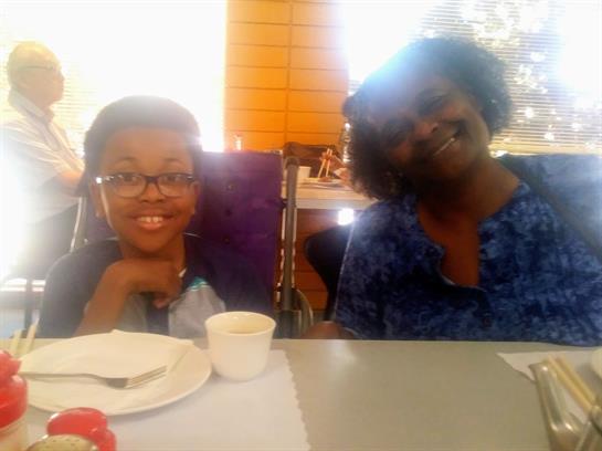 A woman and a child are smiling while sharing a sweet treat in a casual dining setting.