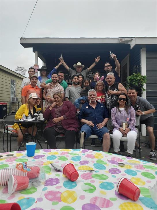 Numerous people enjoying a joyful gathering outside a home, sharing laughter and drinks together.