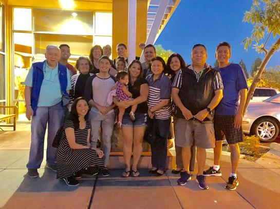 A diverse group of individuals gathers outside a restaurant, smiling and posing together.