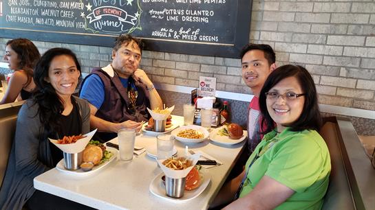Four friends sit around a table with various tasty dishes, sharing laughter and conversation.