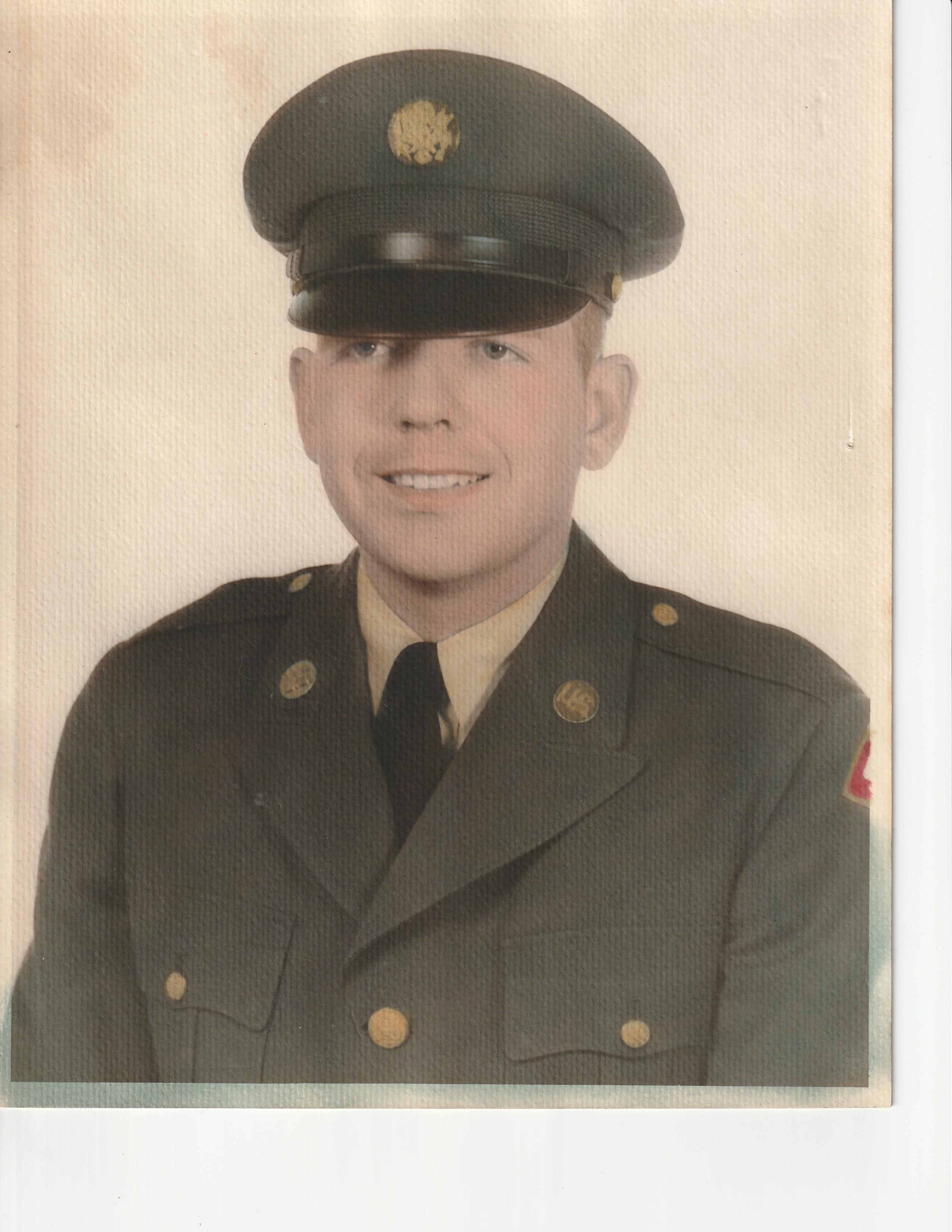 A young soldier, dressed in a military uniform with a hat, poses confidently for a formal portrait.