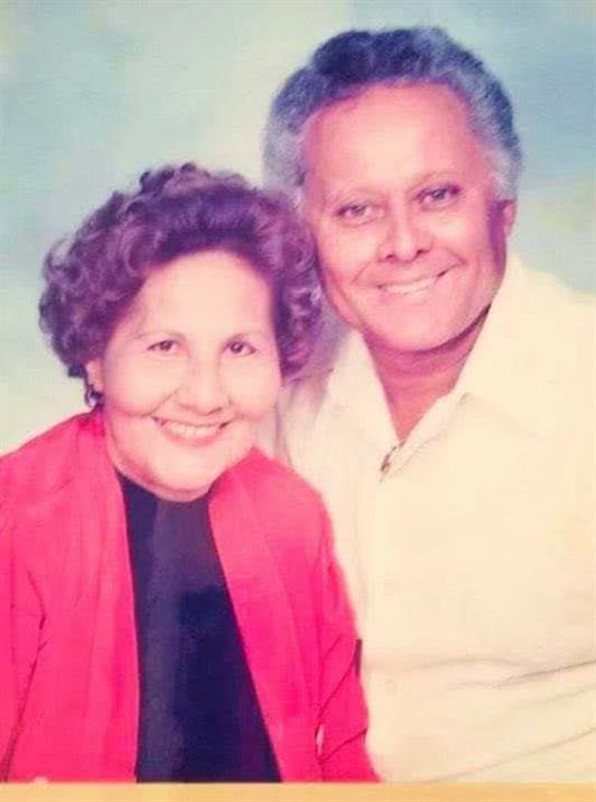 Two seniors share a joyful moment, smiling warmly at the camera while dressed casually.