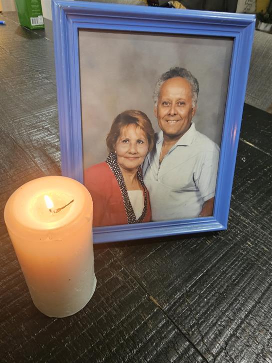 A candle shines beside a framed picture of a smiling couple on a rustic table.