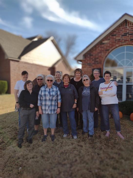 Friends gather outside a house for a joyful moment, showcasing friendship in a relaxed atmosphere.