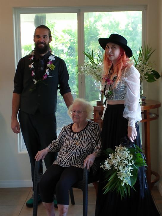 Family members gather around an elderly woman, celebrating together in a warm home atmosphere.