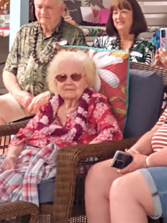 A group of seniors relax together at a lively outdoor gathering poolside, soaking up the sun.