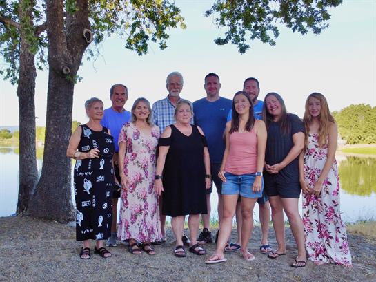 Group of family members posing happily by the lake, enjoying quality time in the sun.