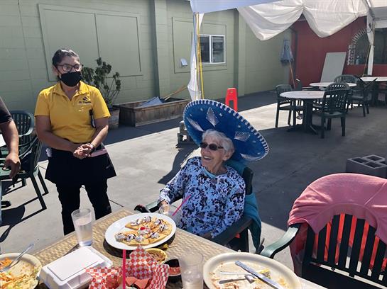 A woman in a wheelchair with a hat and a man in a yellow shirt
