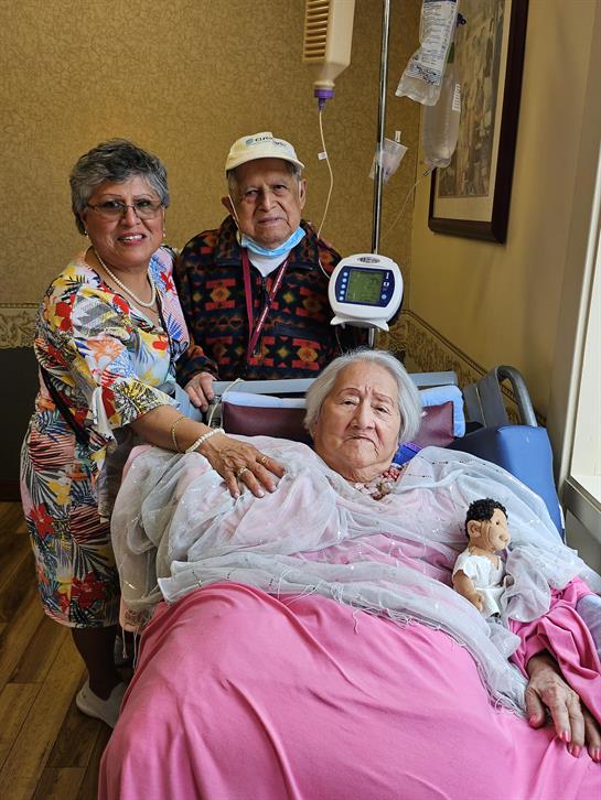 A group of people standing next to a woman in a hospital bed
