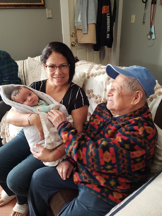 A man and woman sitting on a couch holding a baby