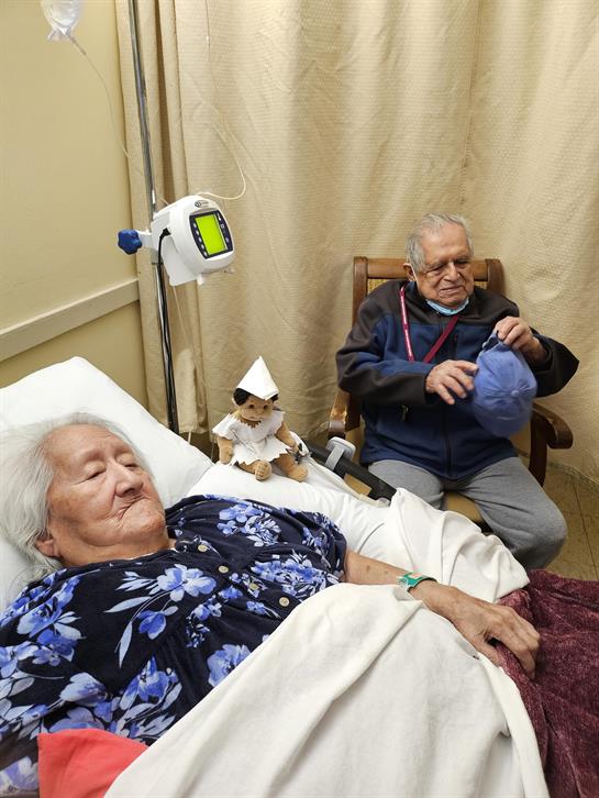 A man sitting in a chair next to a woman in a hospital bed