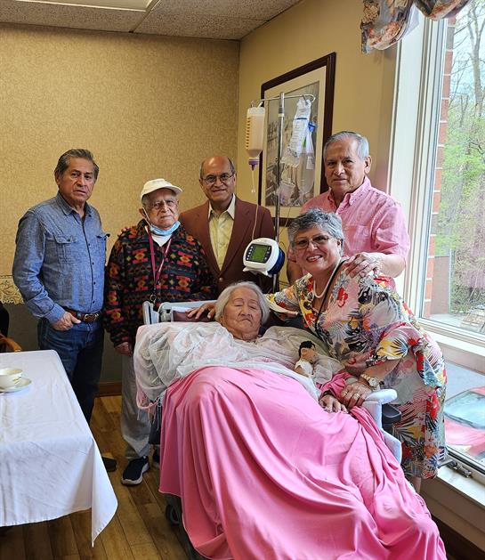A group of people standing around a woman in a hospital bed