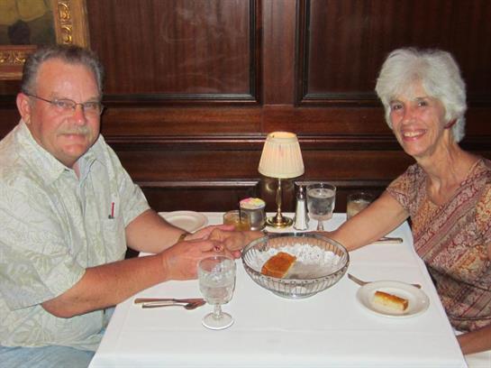A couple shares a romantic dinner, seated at a well-set table with soft lighting.