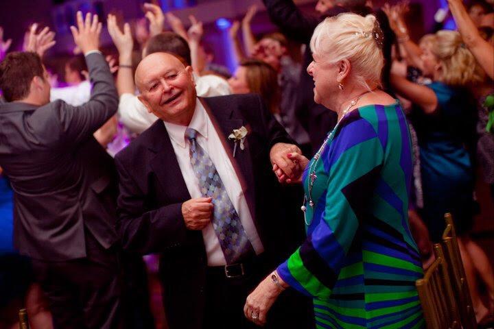 Two seniors dance joyfully together at a vibrant celebration full of energy and laughter.